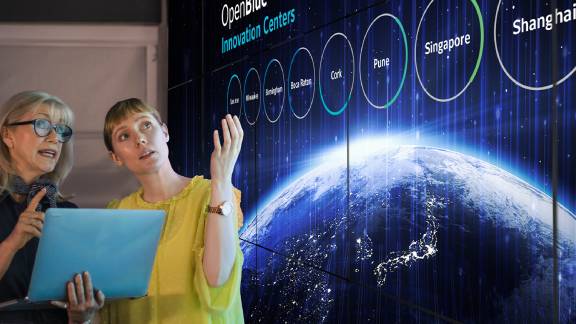 Two female colleagues discussing a presentation on OpenBlue