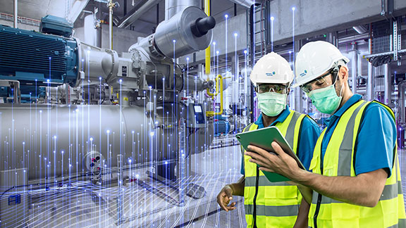 Two factory workers looking at a tablet in a factory