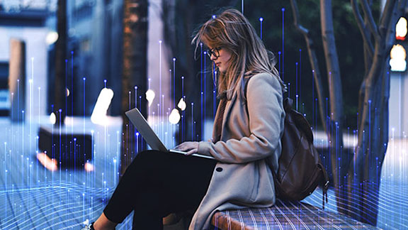 Woman sitting on a bench with a laptop in her lap