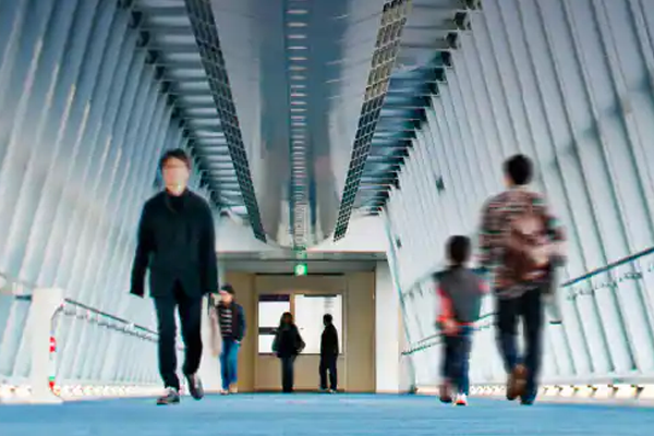 People walking along a long passage in a building
