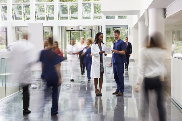 A doctor and a nurse talking in a crowded hospital hallway