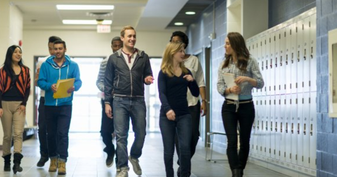 High school students walking along a hallway lined with lockers