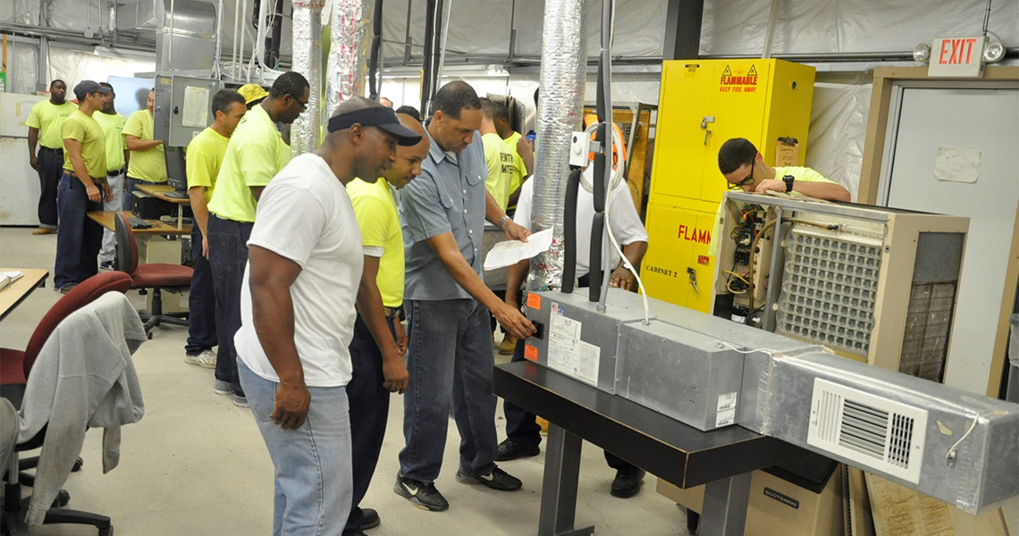 Attendees at an HVAC workshop hosted for former inmates by Johnson Controls, examining HVAC equipment