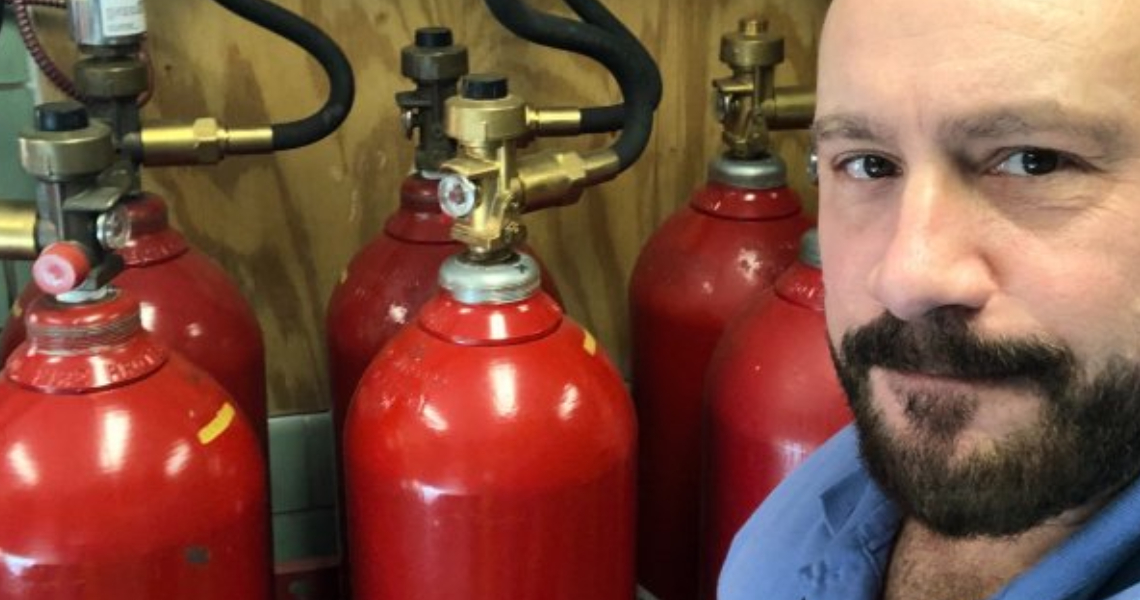 Mike Siragusa, a fire technician at Johnson Controls, standing near a set of fire extinguishers 