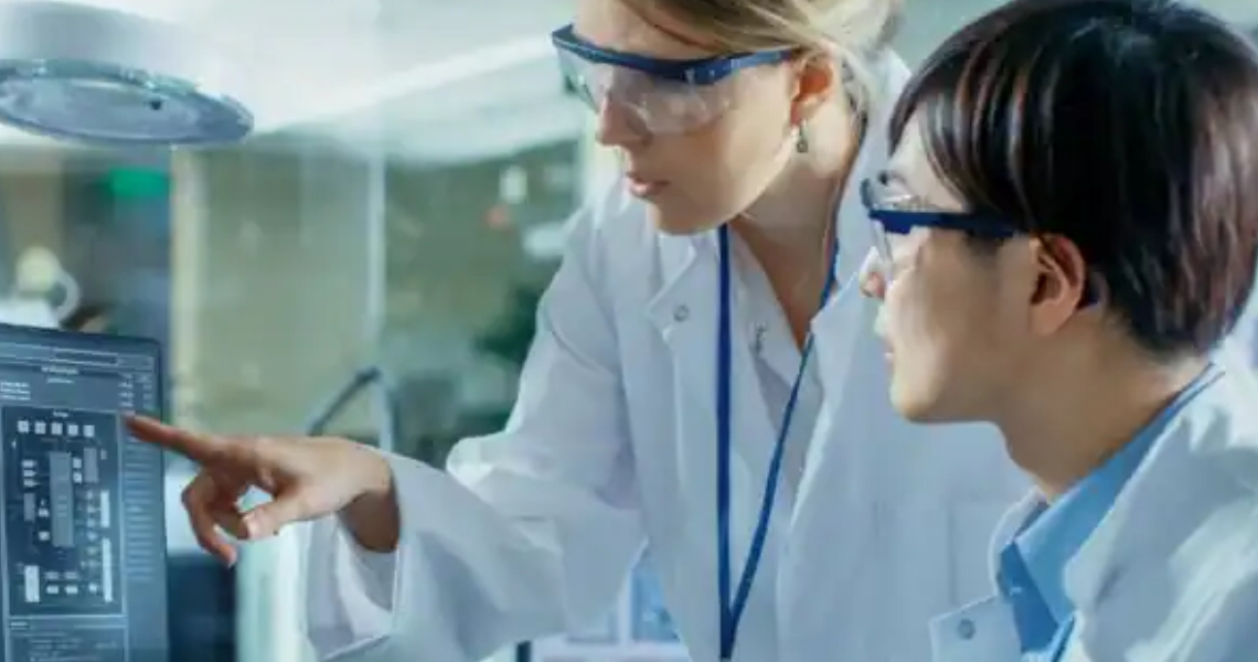 Two female scientists looking at a computer screen in a lab