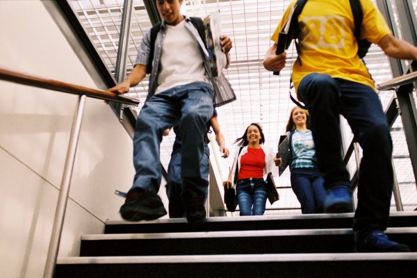 Downward view of students smiling and going down a staircase 