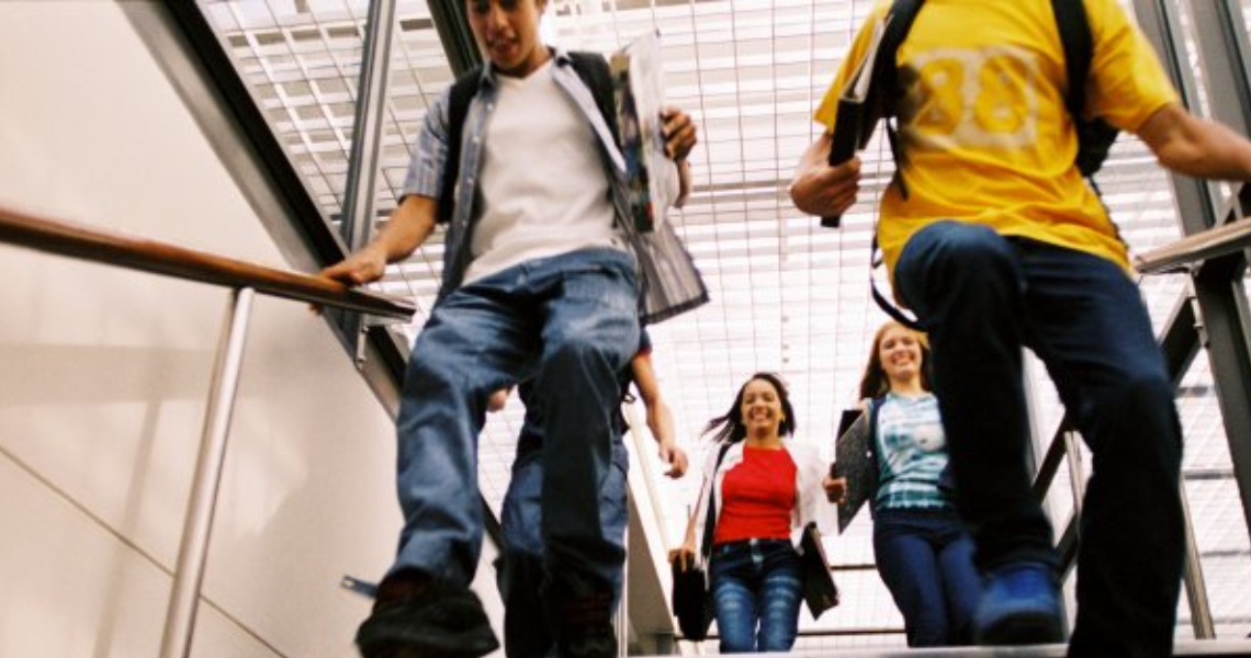 Downward view of students smiling and going down a staircase 
