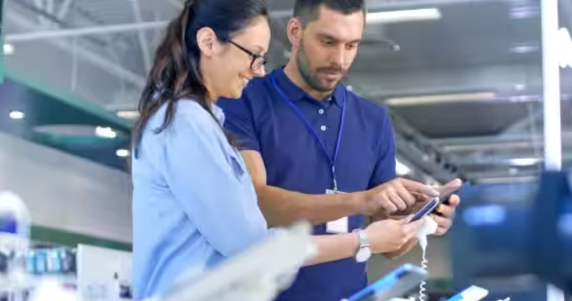 A woman and a male salesperson looking a mobile phones at a store
