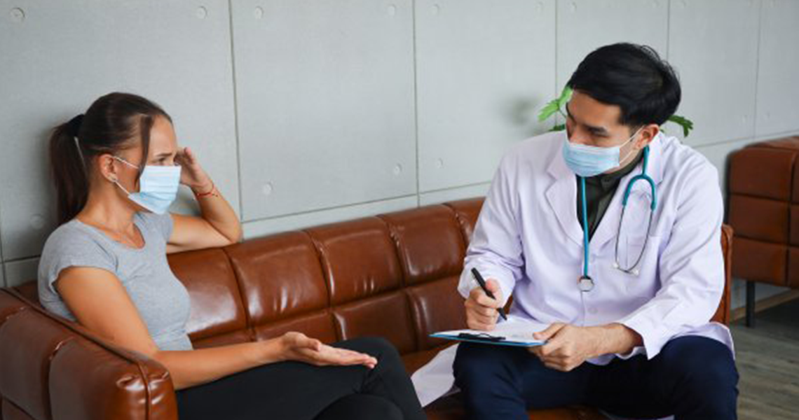 A doctor and a female patient seated on a couch and discussing