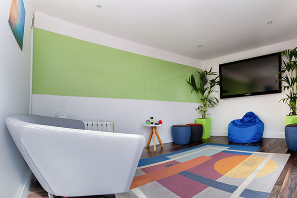 Pictured is one of the dedicated quiet zones, an outdoor area with calming artwork and soft furnishings. This has a dual functionality of being a dedicated quiet working space to help optimise attention and concentration for those who may find it difficult in an open plan shared office space. The team also chose specific plants for the exterior to promote sensory safety. 