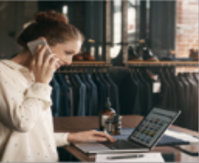 store associate on phone while viewing laptop